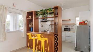 A kitchen with wooden bar stools, a microwave, and a refrigerator.