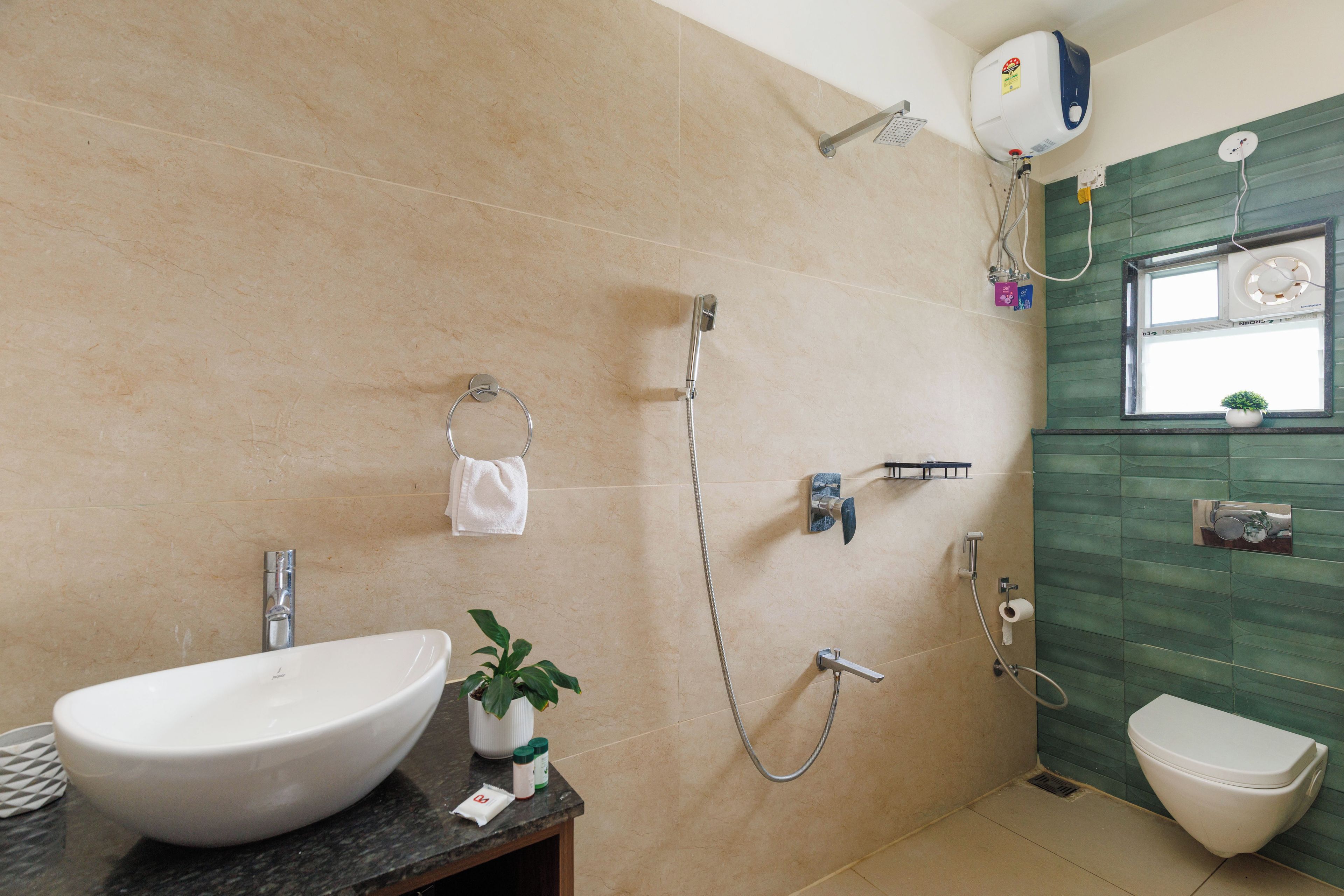A bathroom with a large white sink, a handheld showerhead, a toilet, and a towel rack.