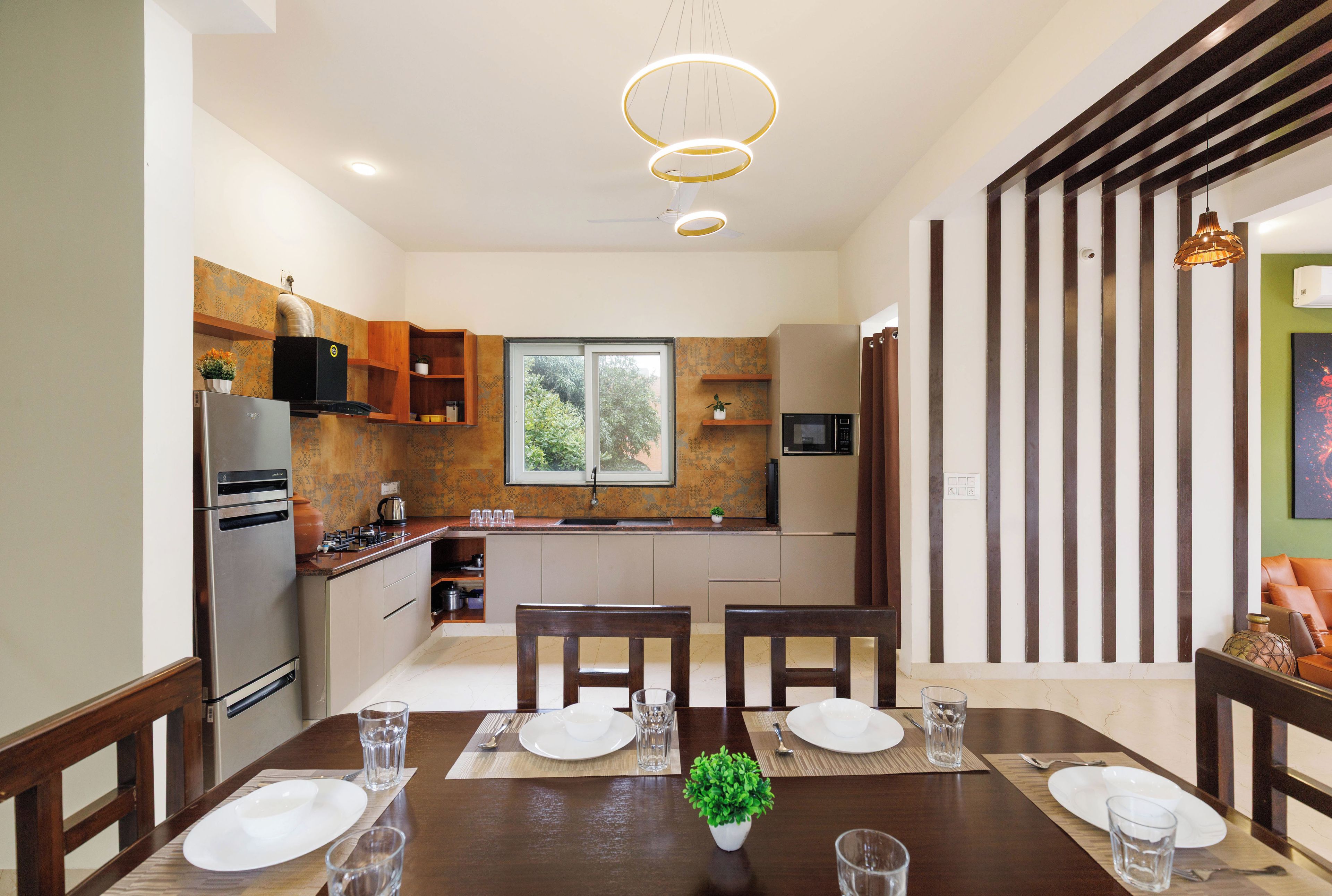 A modern kitchen with a dining area, featuring a central island, built-in appliances, and a large window.