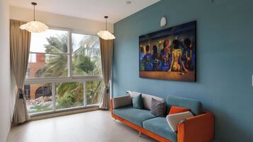 Una sala moderna con un ventanal grande, una pared azul y un sofá con cojines naranja.