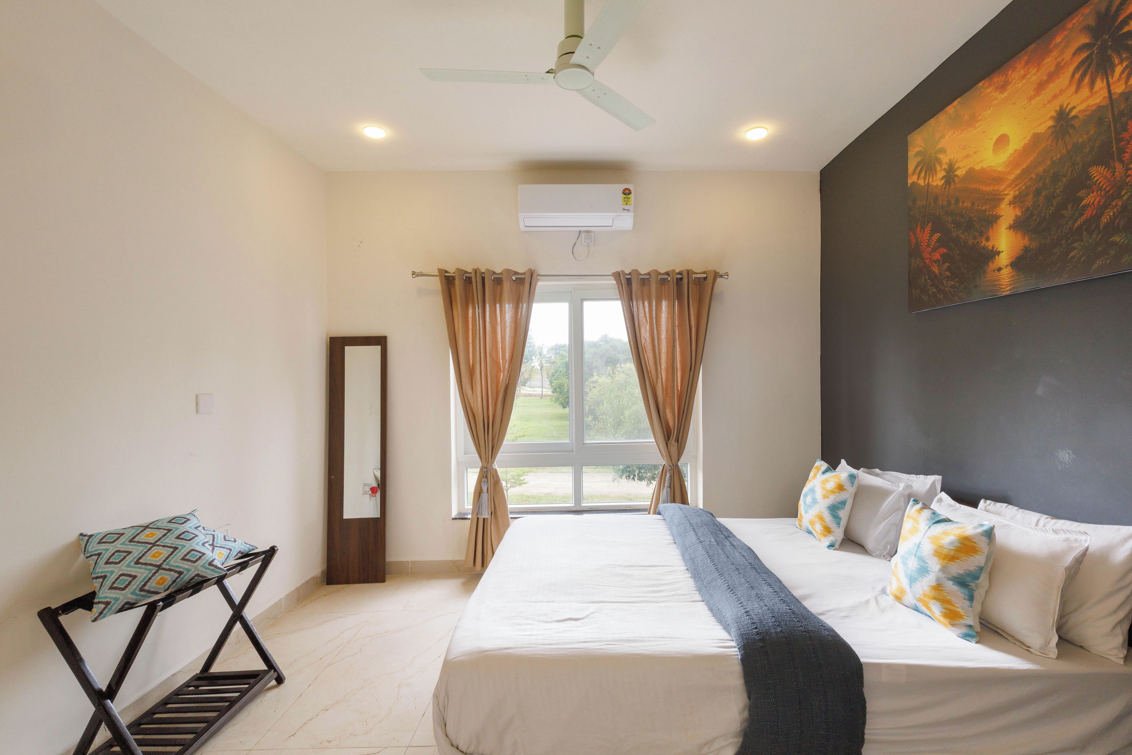 A bedroom with a bed, a chair, a ceiling fan, and a painting on the wall.