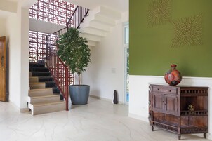 Una escalera con barandilla metálica, una planta en maceta y un mueble de madera con un jarrón decorativo.