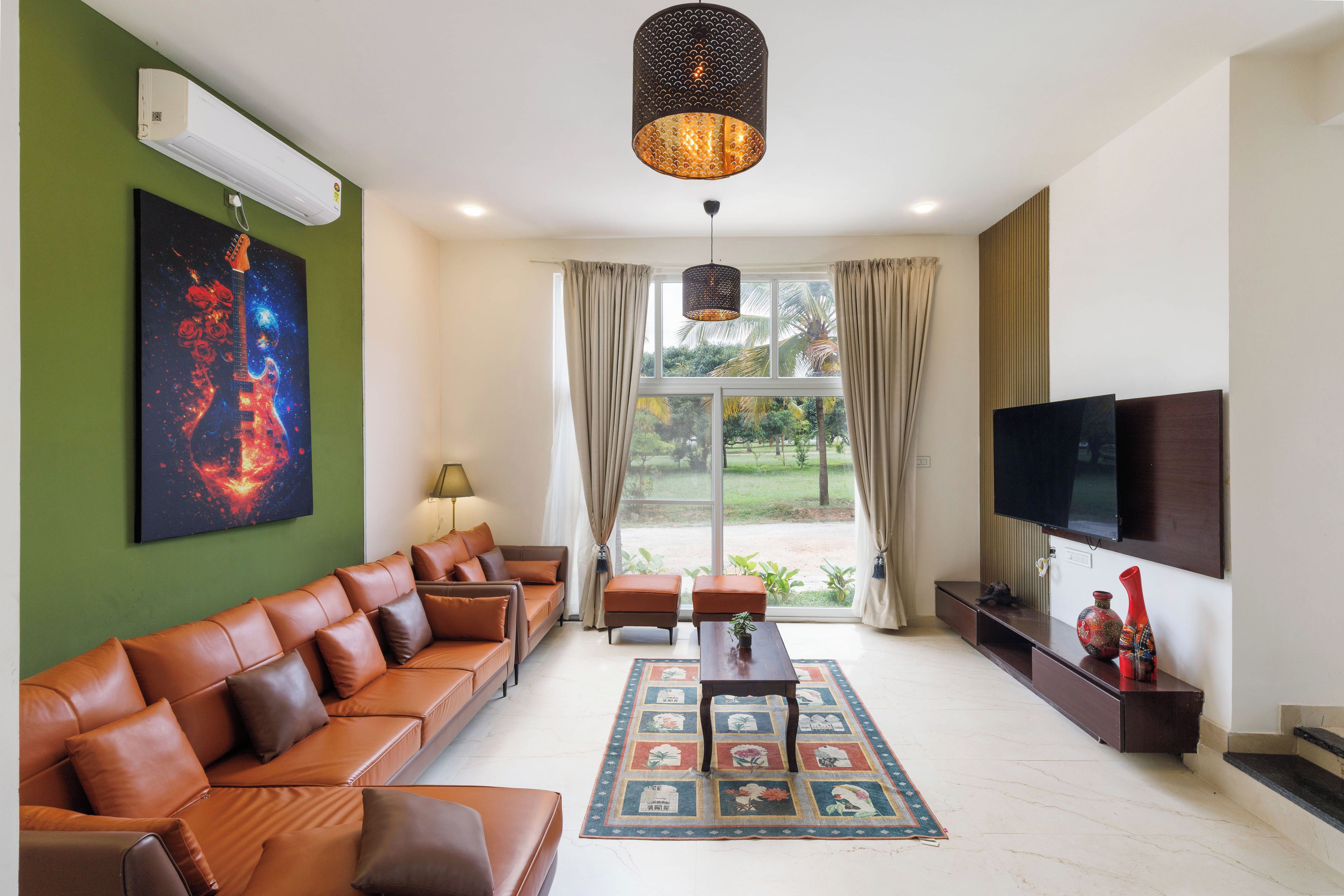 A modern living room with a leather sofa, a flat-screen TV, and a large window with curtains.