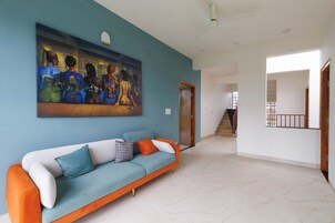 Uma sala de estar com um sofá, um quadro e uma escada que dá para outro cômodo.