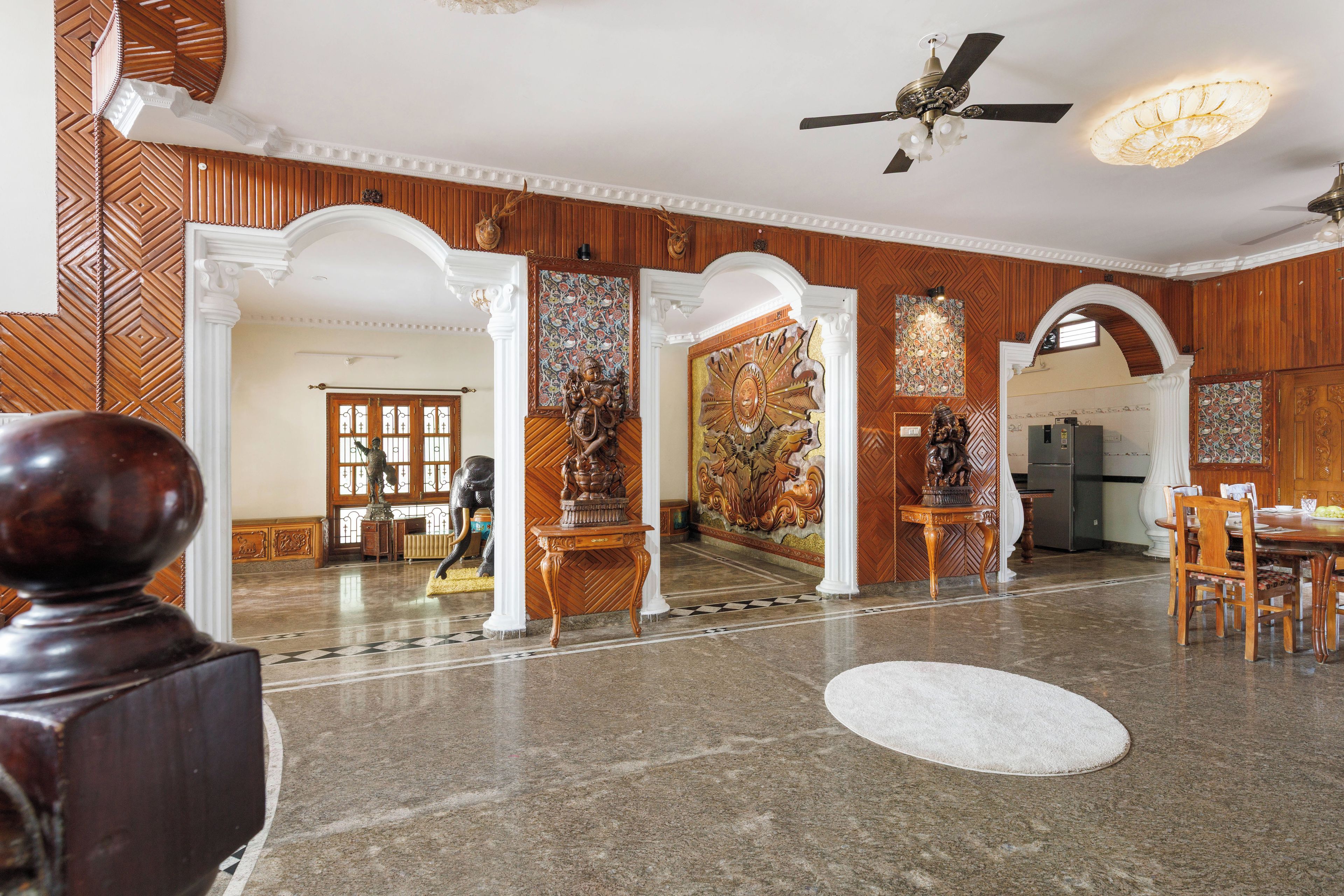 A spacious lobby with a high ceiling, decorative columns, and a central chandelier.