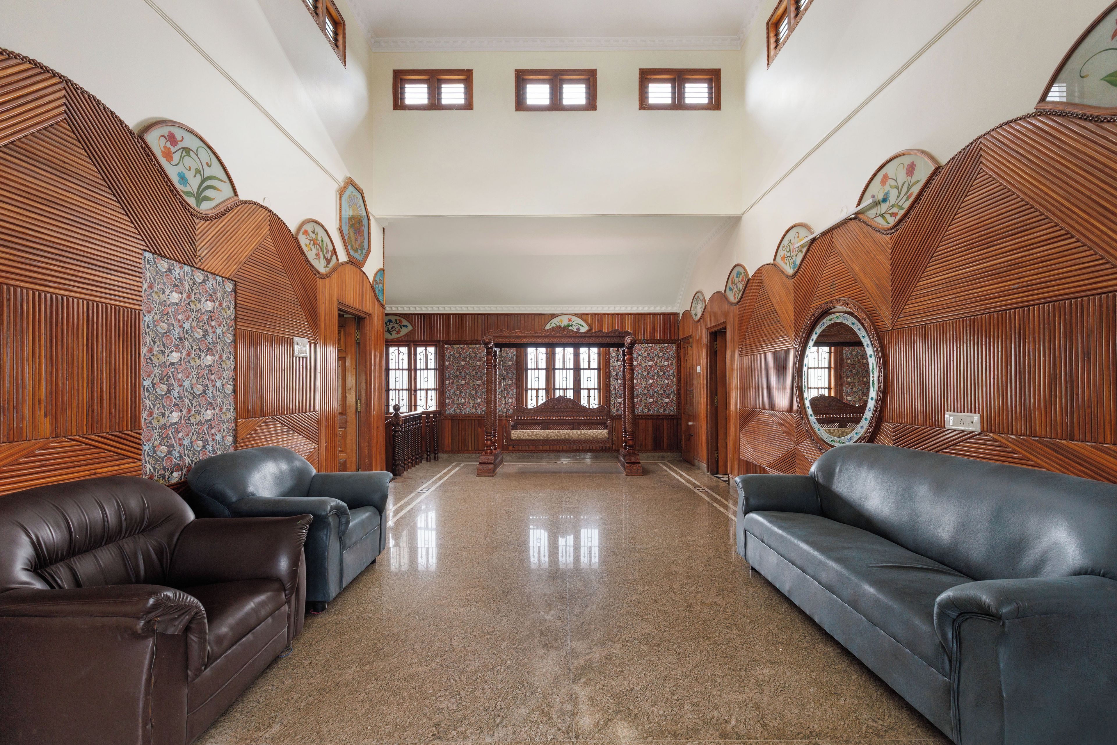 Amplia habitación con techo alto, paneles de madera y una zona de estar central con sofás.