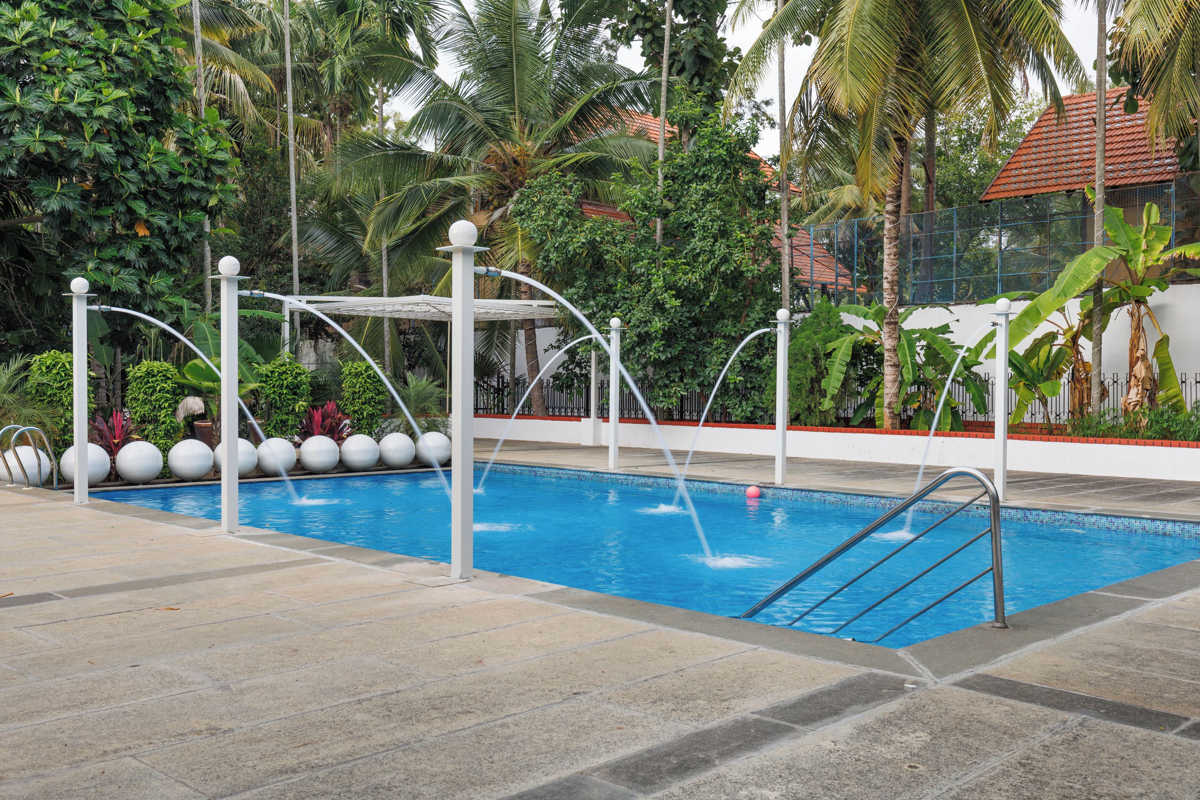 Une piscine à l’eau d’un bleu cristallin, entourée d’une terrasse dallée et d’une clôture blanche.
