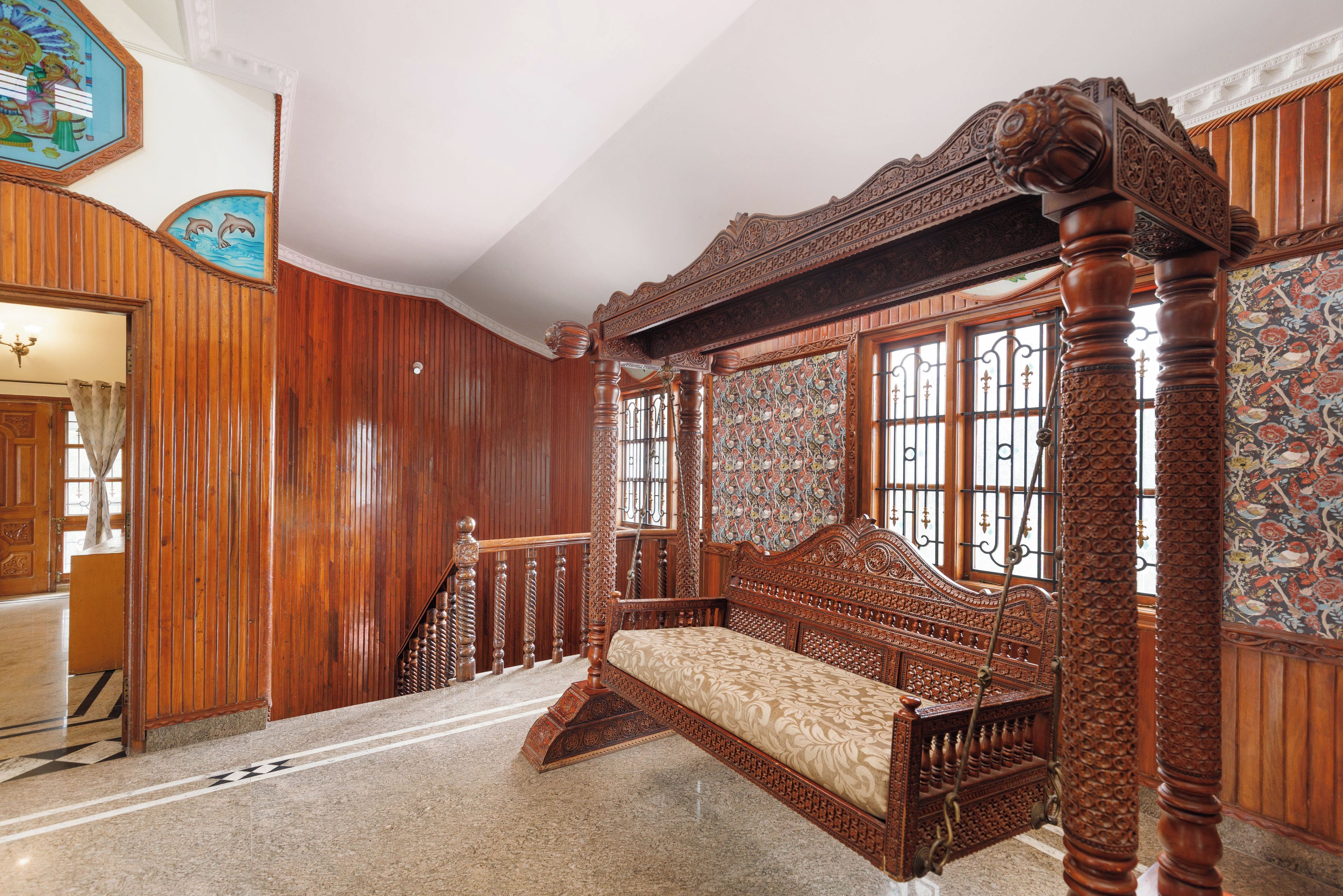 A traditional room with a four-poster bed, wooden paneling, and a patterned tapestry.