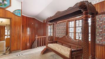 A traditional room with a four-poster bed, wooden paneling, and a patterned tapestry.