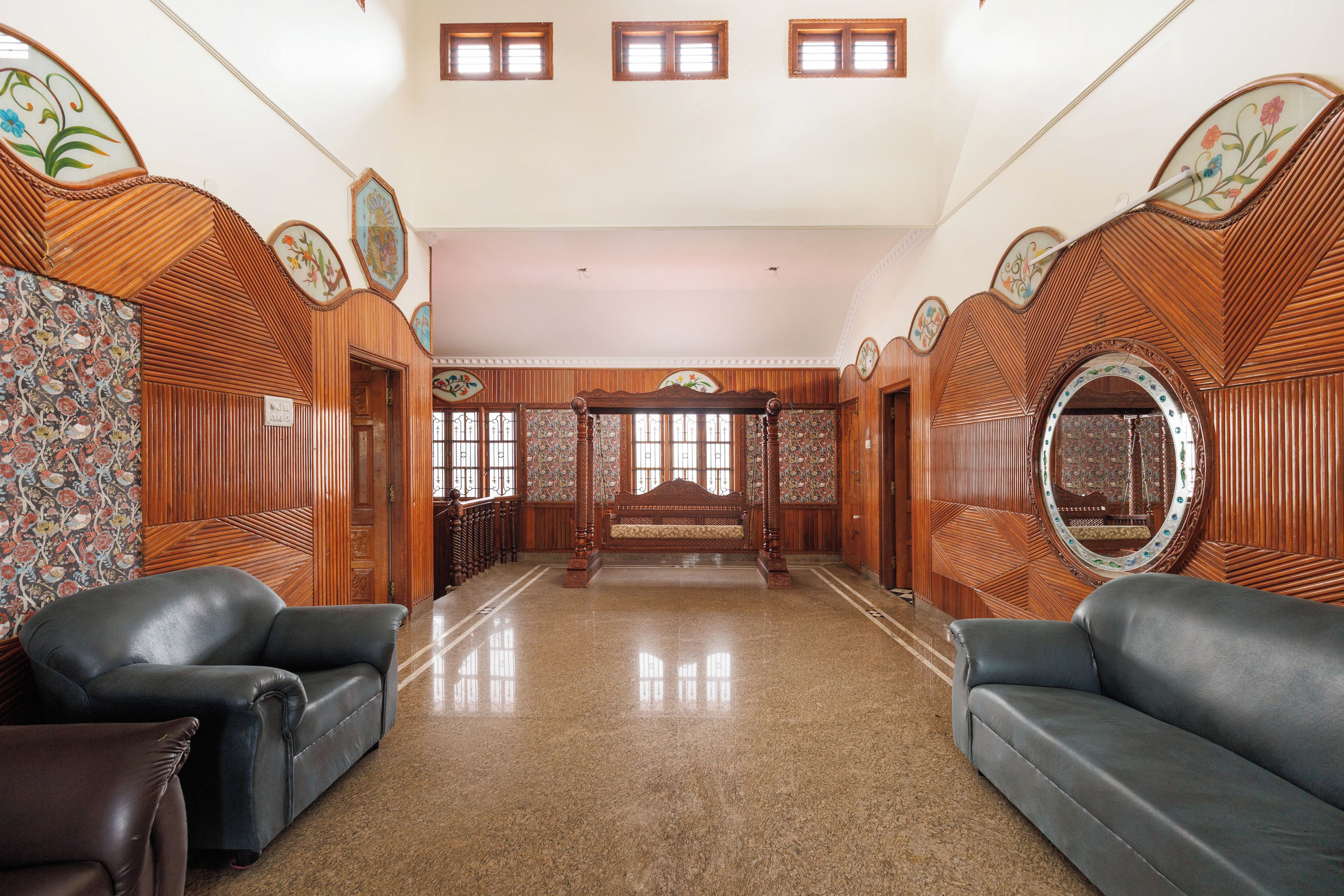 A spacious room with a large bed, two sofas, and a mirror.