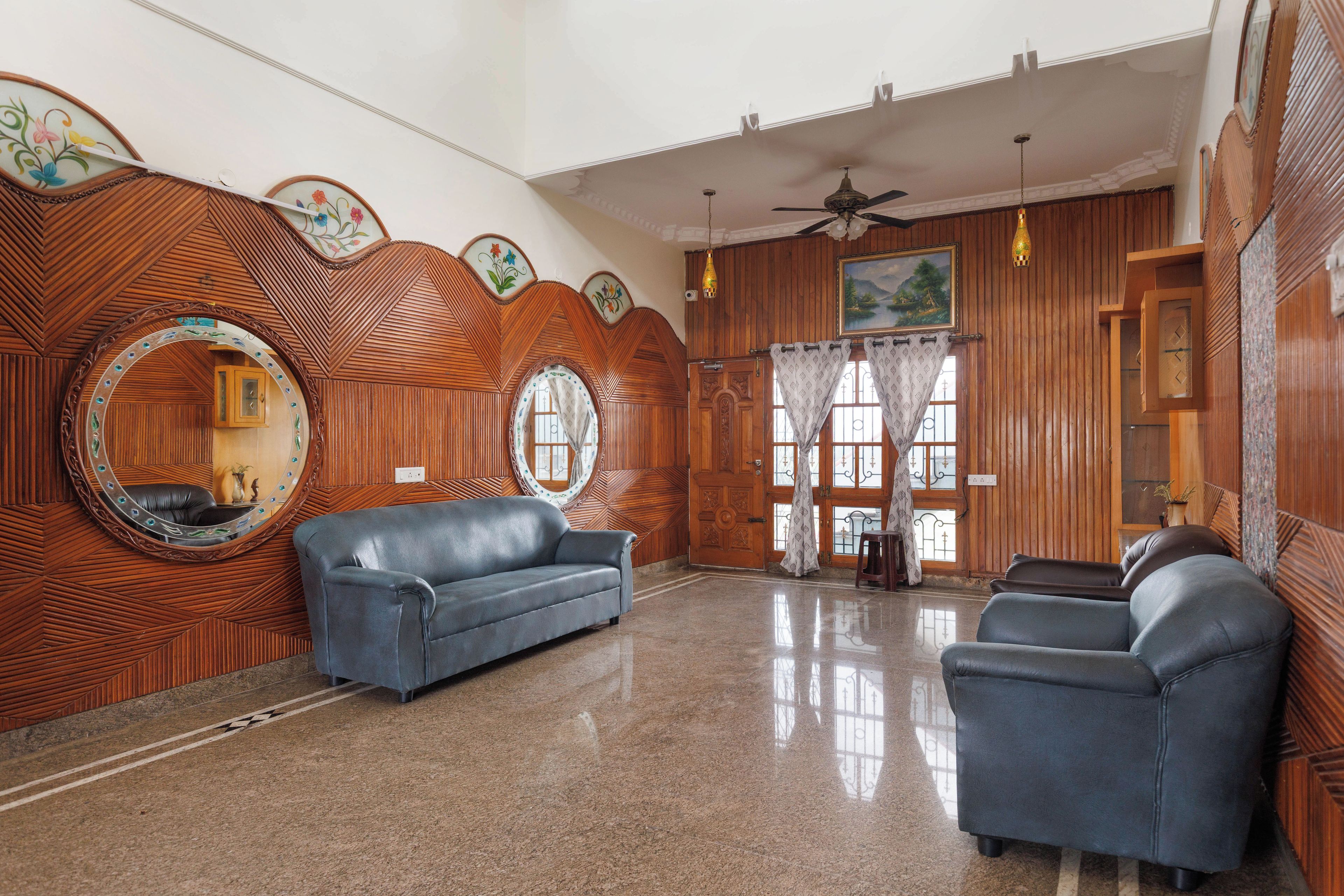 A room with a wooden wall design, a ceiling fan, a sofa, and a dining table.