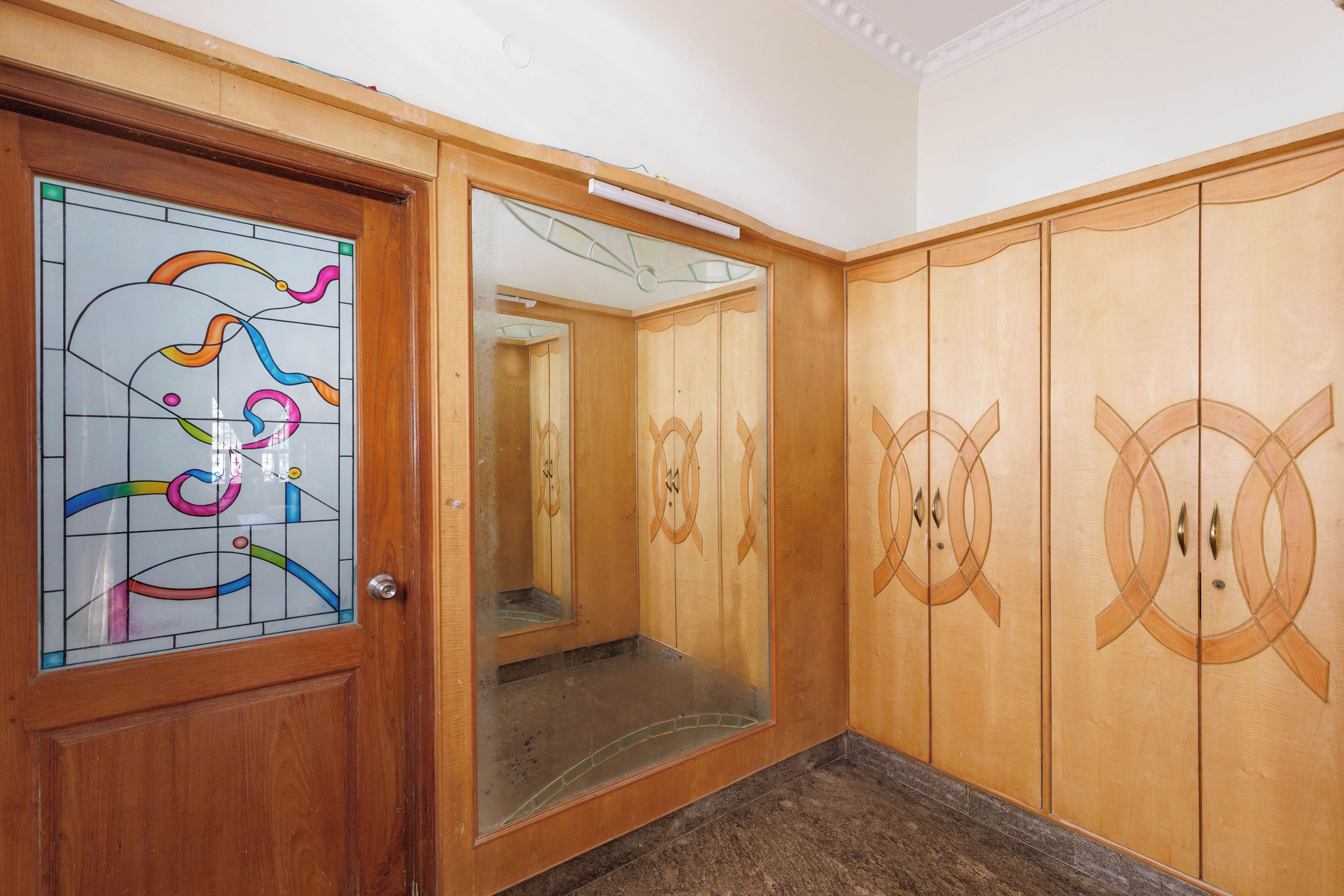A wooden wardrobe with mirrored doors and a stained glass window.