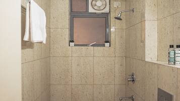 A bathroom with a shower, a towel rack, and a small plant.