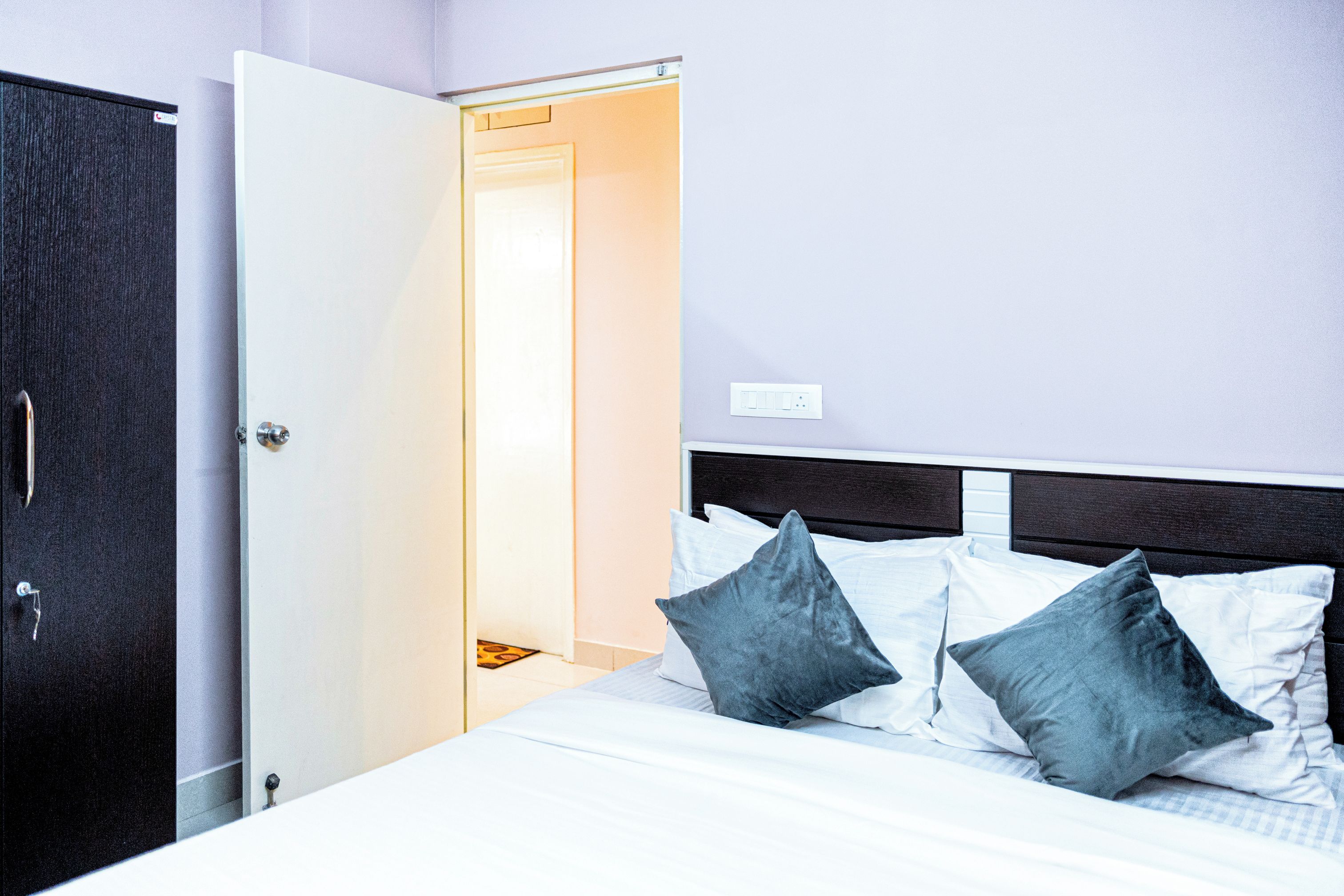 Une chambre d’hôtel comprenant un lit, des oreillers, une armoire et une porte donnant accès à une salle de bain.