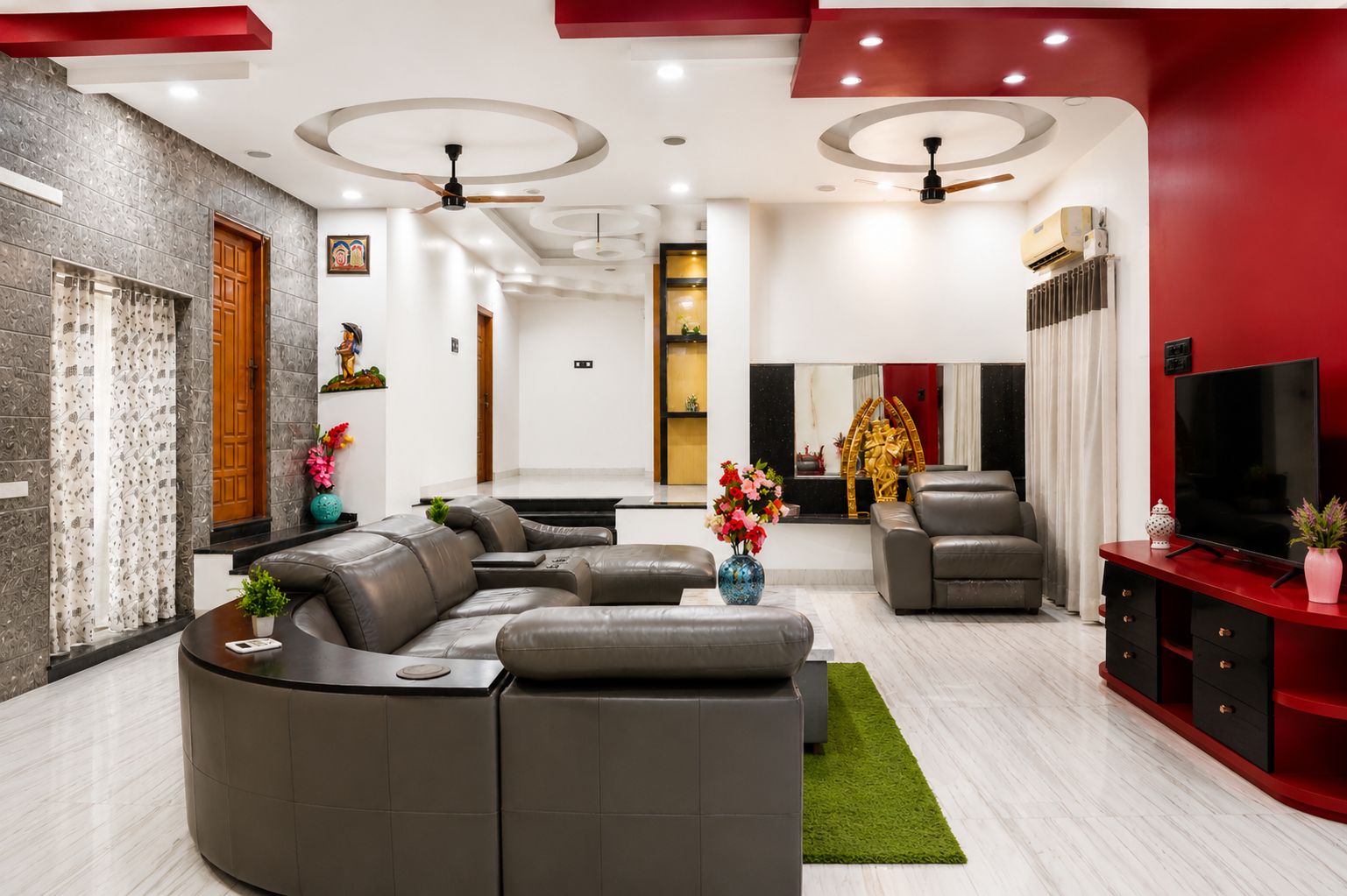 A modern living room with a sectional sofa, a flat-screen TV, and a red accent wall.