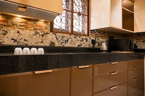 A kitchen with a granite countertop, a stone backsplash, and a stainless steel range hood. - Nectar by Red Olive 3bhk ECR IT Park OMR (Chennai)