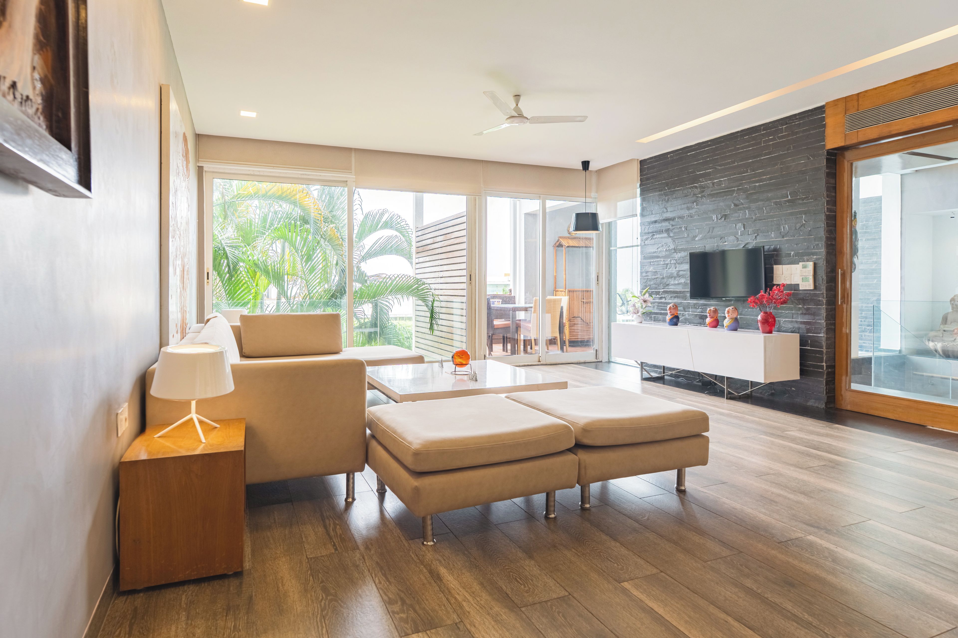 A modern living room with a sofa, a coffee table, and a TV mounted on a brick wall.