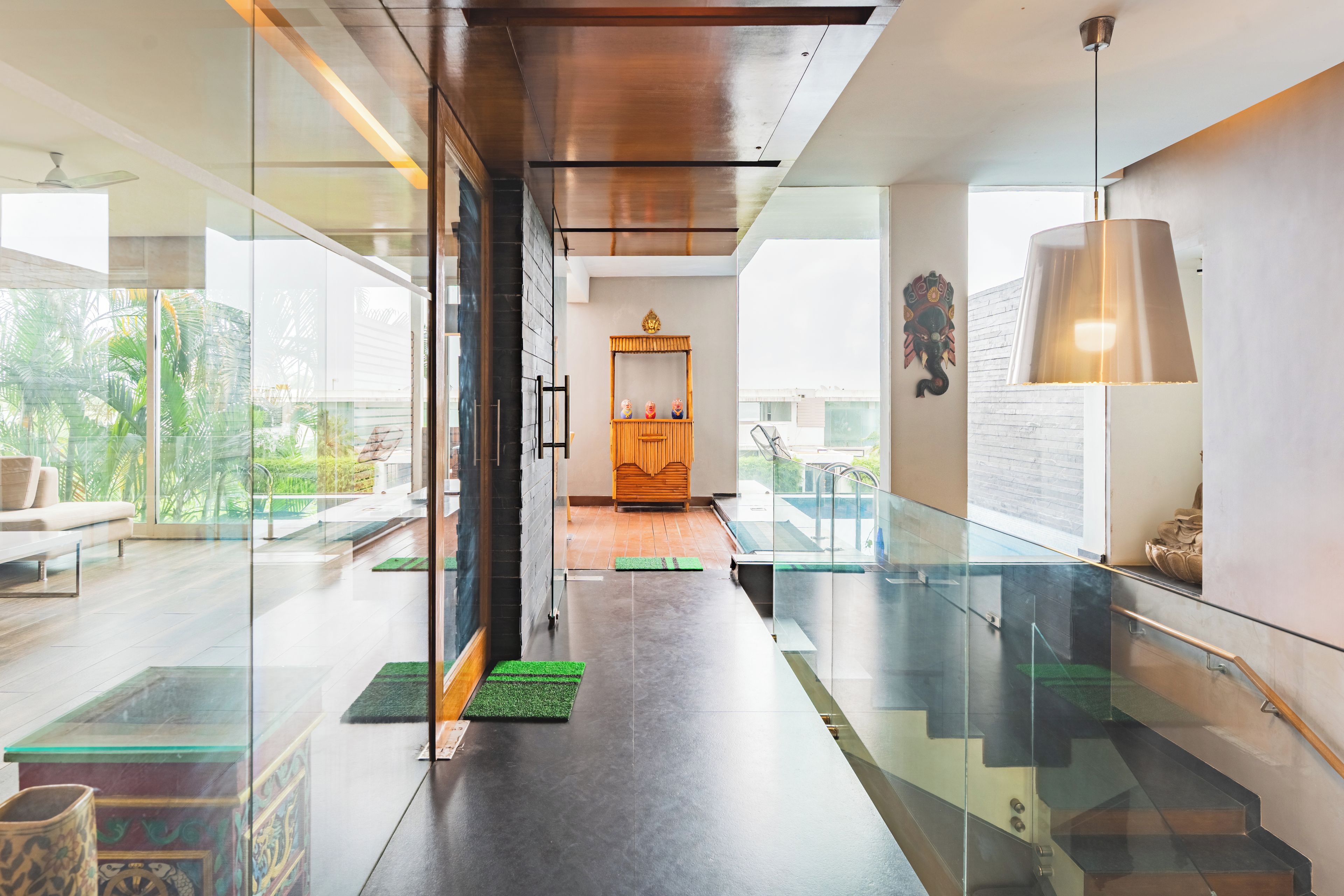 A modern interior with a glass partition, a staircase, and a view of the outdoors.