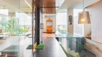 A modern interior with a glass partition, a staircase, and a view of the outdoors.