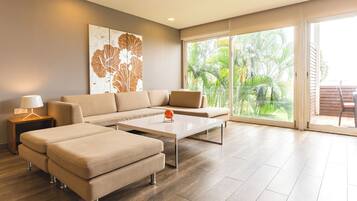 A modern living room with a sectional sofa, a coffee table, and a large window with a view of palm trees.