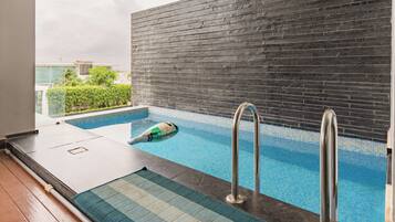 A swimming pool with a tiled floor, metal handrails, and a view of a building in the background.