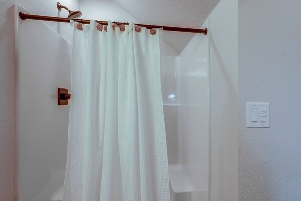 Un baño con cortina de ducha, un picaporte y un interruptor de luz en la pared.