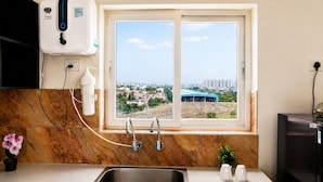 Une cuisine avec une fenêtre, un évier, un système de filtration de l’eau et une vue sur le paysage urbain.