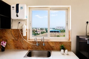 A kitchen with a window, a sink, a water filtration system, and a view of a cityscape. - The Icon by Redolive 2bhkkoyambeduit Parkdlf (Chennai)