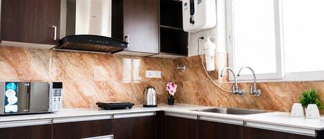 Una cocina moderna con alacenas de madera oscura, una campana extractora de acero inoxidable, un microondas y un dispensador de agua empotrado.