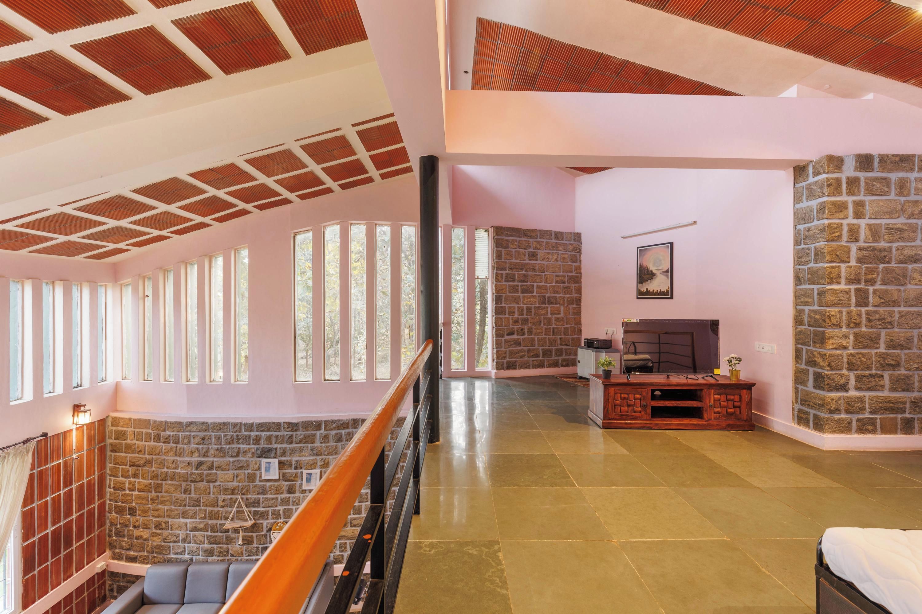Un interior espacioso con techo alto, paredes de piedra y una escalera de madera.
