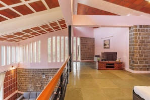 Un interior espacioso con techo alto, paredes de piedra y una escalera de madera.