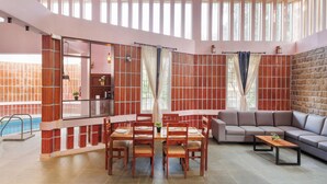 A spacious living area with a dining table, chairs, a sofa, and a pool. - The Rustic Ridge Villa by Stayjadepool1hr E-city (Hosur)