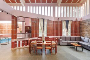 Ampla sala de estar com mesa de jantar, cadeiras, sofá e piscina.