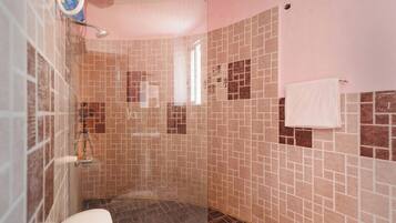 A shower with a glass door, tiled walls, and a white towel hanging on the wall.