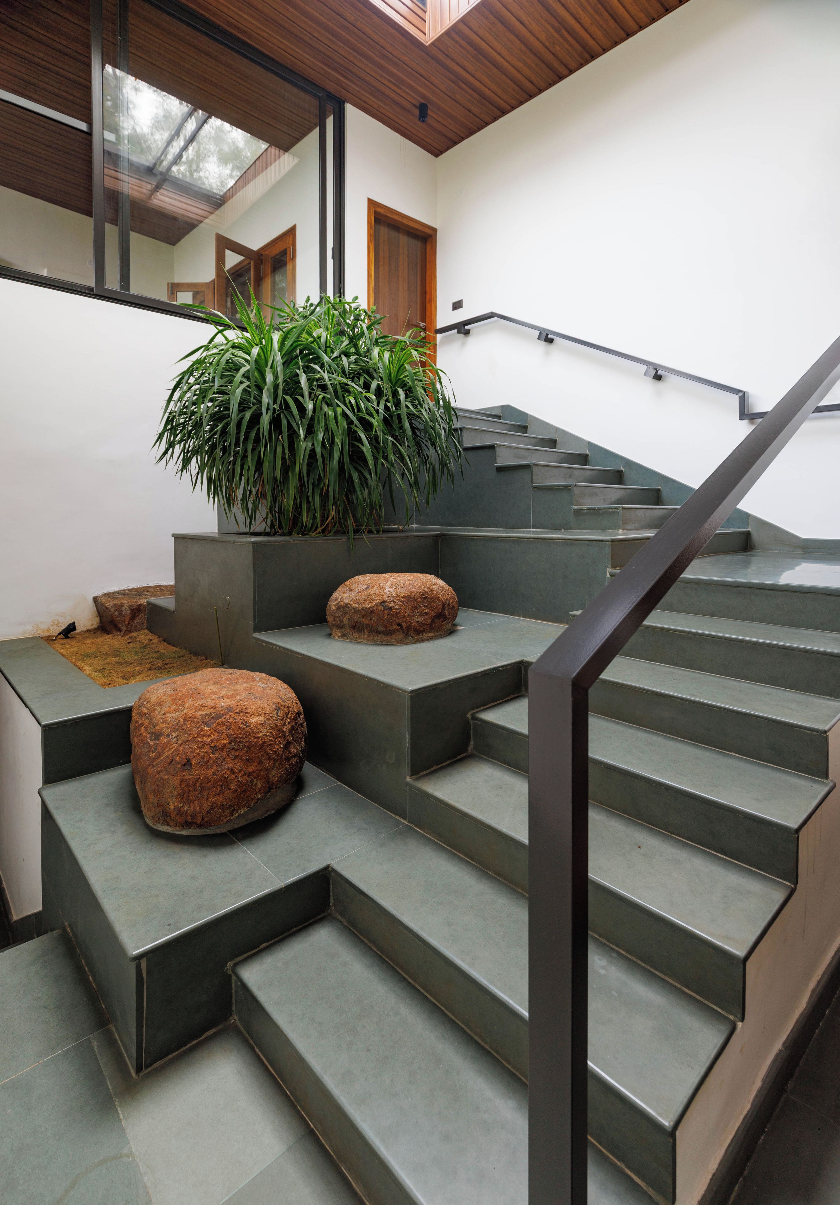 Una escalera de diseño moderno, con barandilla de metal y escalones de piedra.