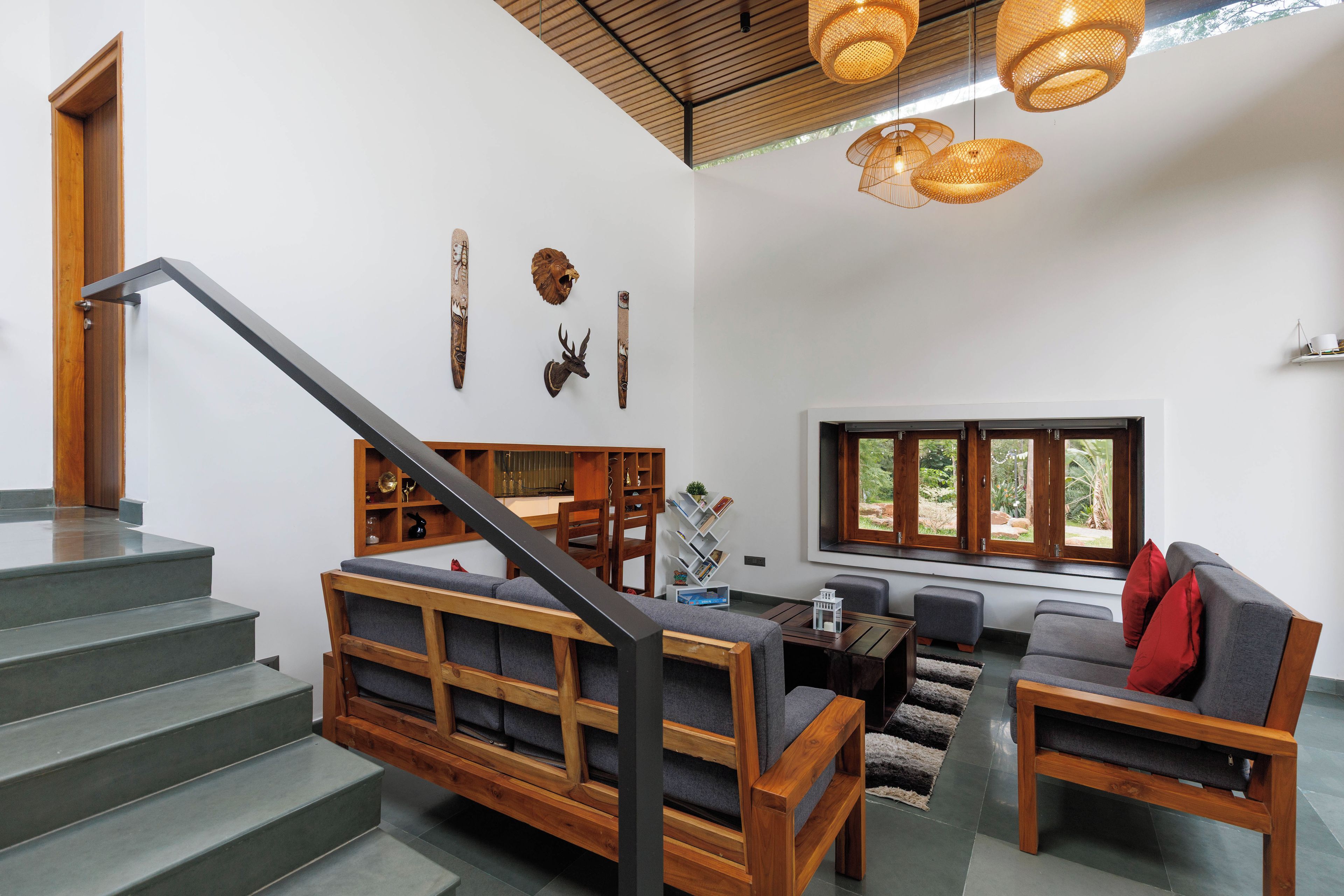 Un interior moderno con una escalera, muebles de madera y vistas al exterior.
