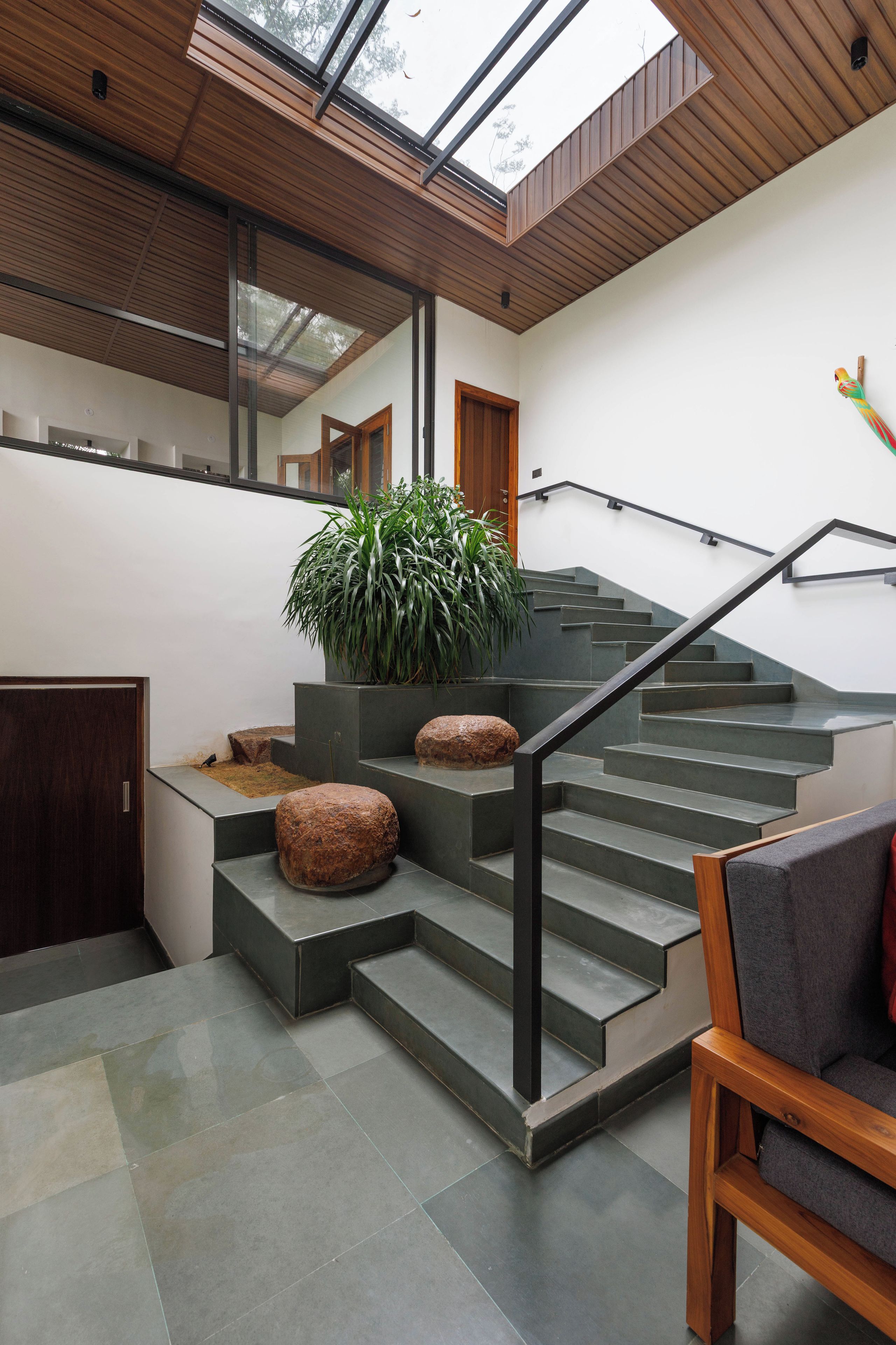 Un interior moderno con una escalera, una planta en maceta y un banco de madera.