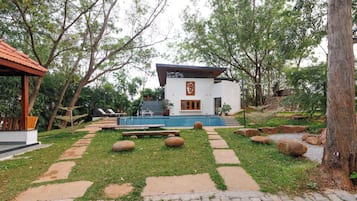 Un edificio moderno con piscina, rodeado de árboles y un sendero de piedra.