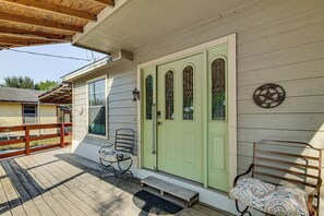 A wooden porch with a green door, a bench, and a small table.