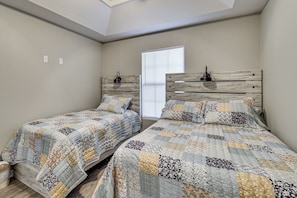A bedroom with two single beds, a wooden headboard, a window with blinds, and a skylight.