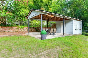 A covered patio with a table and chairs, a potted plant, and a brick wall.