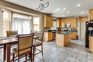 A spacious kitchen with wooden cabinets, a central island, and a dining area with chairs. - Spacious Group Getaway Near Grounds For Sculpture (East Windsor)