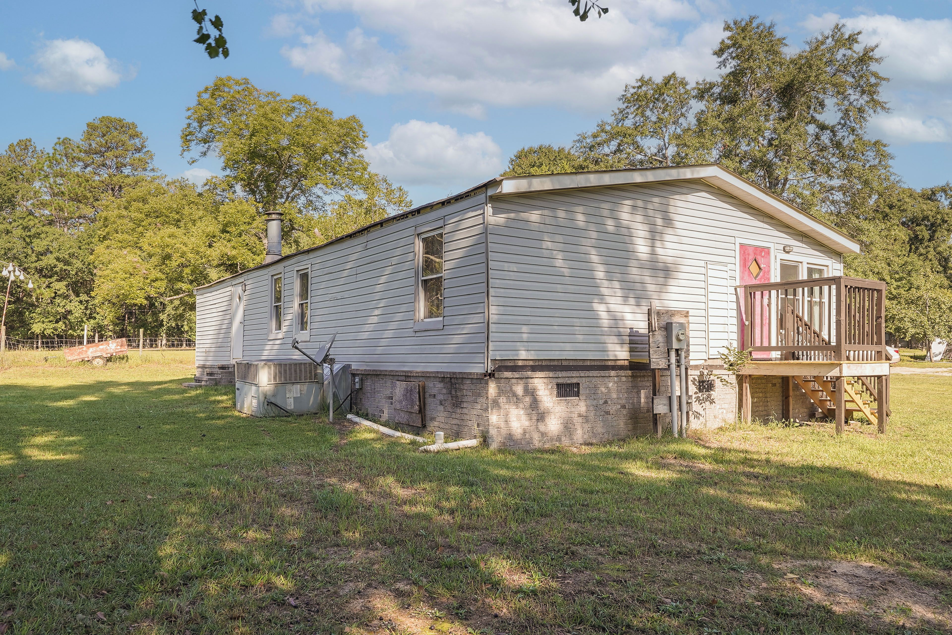 A single-story building with a brick foundation, a chimney, and a small porch with a railing.