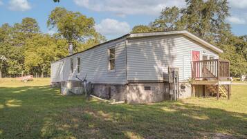 A single-story building with a brick foundation, a chimney, and a small porch with a railing.