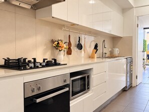 A modern kitchen with a gas stove, microwave, oven, and dishwasher. - Stylish and Cozy Waterloo Apartment with Balcony (Waterloo)