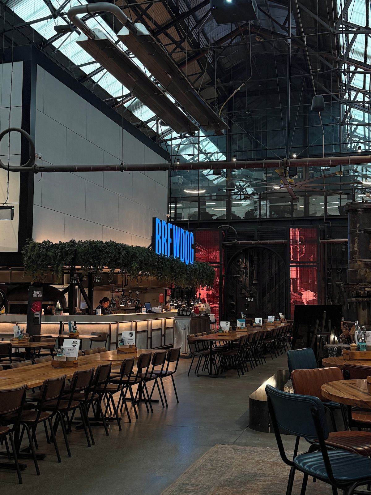 An indoor space with a bar area, seating arrangements, and a visible sign reading 'BREWDOG'.