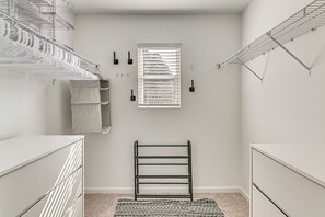 Un closet pequeño con estantes metálicos, un tendedero y un ventanal.