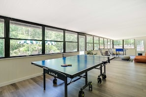 A ping pong table with wheels in a room with large windows and a view of greenery outside. - Pelican House: Waterfront w/ Paddleboat and Kayaks (Homosassa)