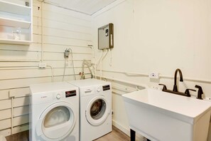 A laundry room with two Bosch washing machines, a water heater, and a white sink with a faucet. - Pelican House: Waterfront w/ Paddleboat and Kayaks (Homosassa)