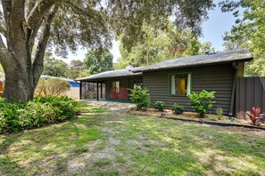 A house with a fenced yard, a large tree, and a small garden area. - Pelican House: Waterfront w/ Paddleboat and Kayaks (Homosassa)
